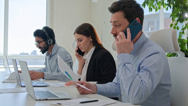 Professional team businessmen and businesswoman solving business issues sales answer mobile phone group diverse workers talking customer service use cell line and laptop workflow in office call center