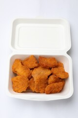 Delicious chicken nuggets in takeaway container on white background, top view