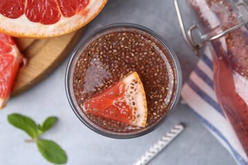 Glass of drink with chia seeds and grapefruit on grey table, flat lay