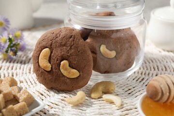 Tasty chocolate cookies with cashew on wicker mat, closeup