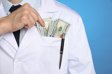 Corruption concept. Doctor putting dollar banknotes into his pocket on blue background, closeup