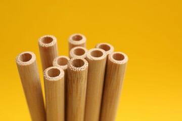 Bamboo drinking straws on yellow background, closeup