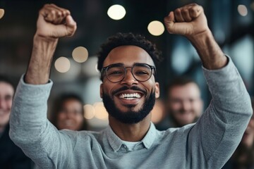 A joyful person with raised arms smiles widely, epitomizing success and happiness in a casual setting with colleagues, conveying optimism and achievement.