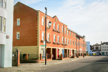 Modern brick town houses with colourful wooden front doors along a street on a cloudy winter day