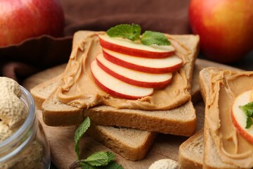 Tasty sandwiches with peanut butter, apples and mint on table, closeup