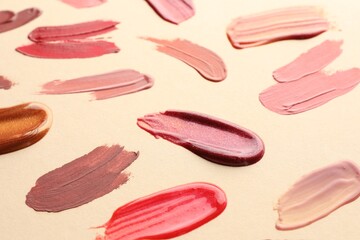 Samples of different lip products on beige background, closeup