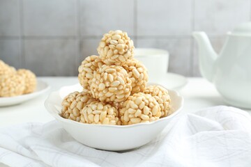 Tasty puffed rice balls in bowl on table, closeup