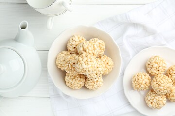 Tasty puffed rice balls served on white wooden table, flat lay