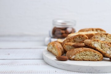 Tasty almond biscuits (Cantuccini) and nuts on light wooden table, closeup. Space for text