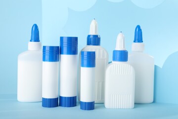 Bottles and sticks of glue on light blue background