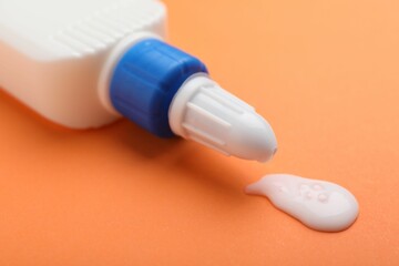 Bottle of glue on orange background, closeup