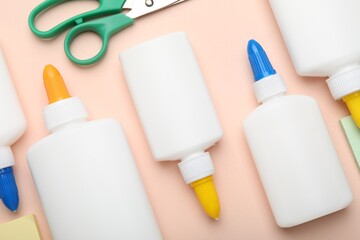 Bottles of glue, scissors and notes on beige background, flat lay