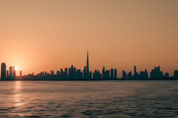 Obraz premium Stunning view of Dubai skyline with warm Pastel Sunrise colors, Beautiful, golden sunset view of the modern skyline at Dubai