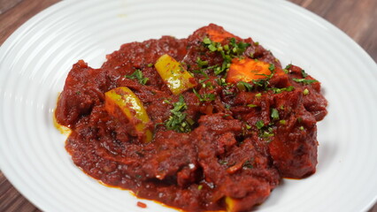 Vibrant dish filled with red tomato-based sauce, featuring chunks of meat and colorful bell peppers, garnished with fresh green herbs. set a warm wooden table backdrop.