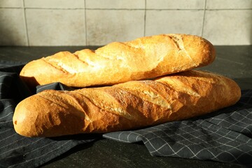 Freshly baked baguettes on black table, closeup
