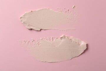 Cream on pink background, top view. Samples of cosmetic product