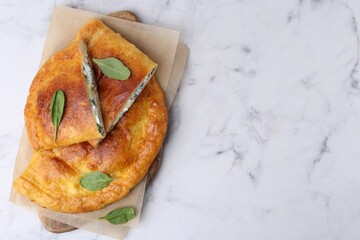 Tasty calzones with cheese and basil on white marble table, top view. Space for text
