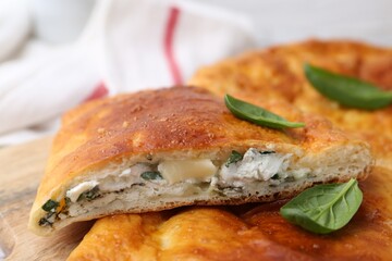 Pieces of tasty calzone with basil and cheese on table, closeup