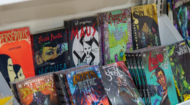
9th Comic Con Convention In GUAYAQUIL, ECUADOR - AUG 04, 2024 - Close-up of a variety of graphic novels and comic books on a shelf, featuring titles like Maus, Persepolis, and Adventure Time. Perfect