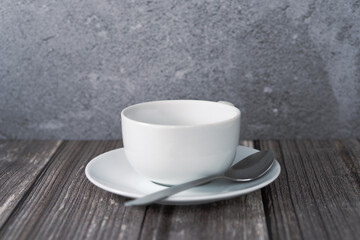 Isolated close up of coffee cup centered with saucer and spoon on a wooden surface