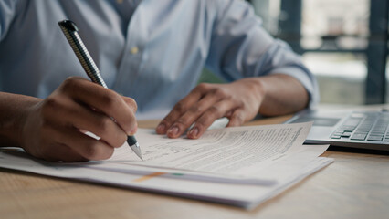Close up unrecognizable man businessman writing paperwork report on desktop male hands signing...