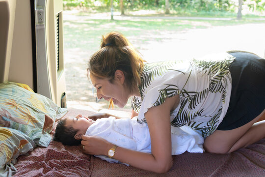 Concept: mirror neurons in babies, a mom playing with her daughter shouts A and her baby imitates her. lying on the bed of a motorhome RV traveling as a family in nature. Camper life.