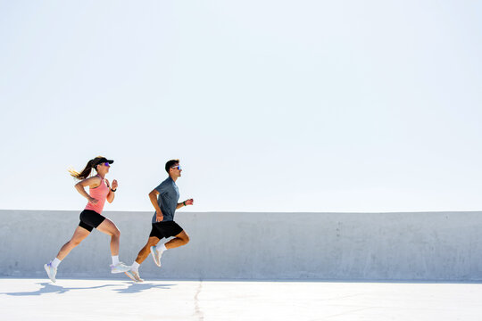 Couple jogging on a bright sunny day along a minimalist urban track