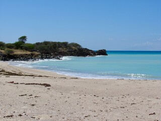 Tropical beach with rocky coastline and turquoise waters.