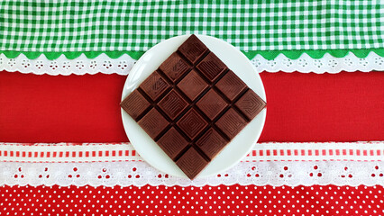 Chocolate bar on the red and green decorated background. Space for text.

