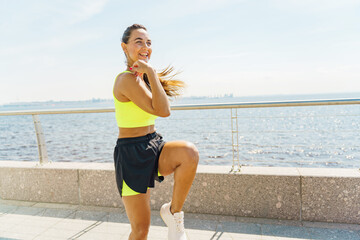 Woman in bright sportswear exercises along scenic waterfront path during sunny day