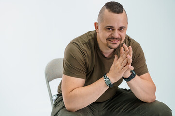 Confident Man in Casual Clothing Sitting on a Chair with Hands Together