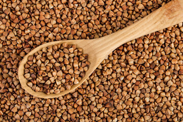 Raw buckwheat in wooden spoon as a background. Top view. Flat lay
