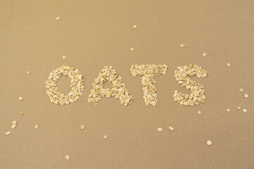 Oats word spelled out in dry rolled oats on brown background