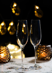 concept of celebrating christmas and new year, two glasses of champagne on the background of candles and colorful garlands, warm home traditional festive atmosphere