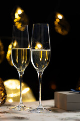 concept of celebrating christmas and new year, two glasses of champagne on the background of candles and colorful garlands, warm home traditional festive atmosphere