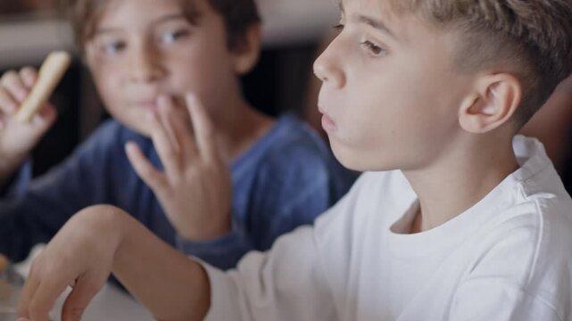 Two young boys engaged in the process of making tiramisu. One tastes the ingredients while the other observes, showcasing the joy of culinary creativity and family bonding in the kitchen.