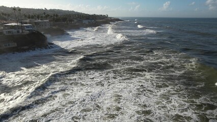 Aerial view of rugged coastline with crashing waves.