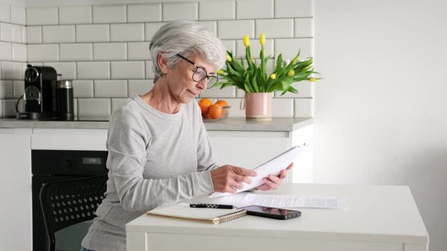Elderly Woman With Grey Hair Managing Paperwork And Calculating Bills