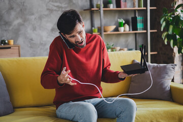 Young man in red sweater handling technical issues while enjoying a relaxed day at home