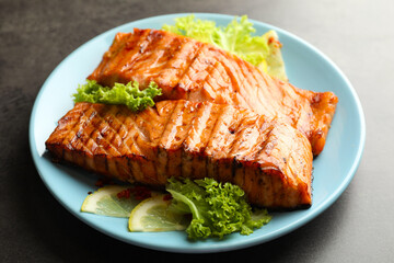 Delicious grilled salmon fillets with lettuce and lemon on grey table, closeup