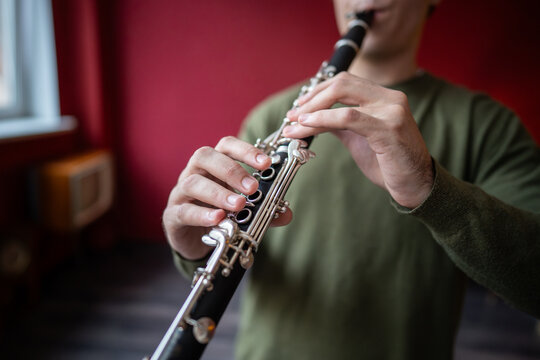 Clarinet player. Clarinetist hands playing flute woodwind music instrument closeup at home, soft focus. Musical instruments. Guy plays the oboe in education classroom. Hobby. 