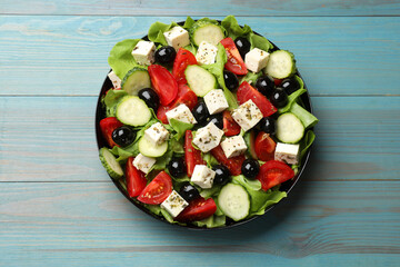 Delicious salad with feta cheese on light blue wooden table, top view