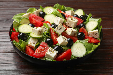 Delicious salad with feta cheese on wooden table, closeup