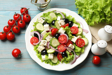 Delicious salad with feta cheese and ingredients on light blue wooden table, flat lay