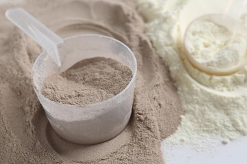 Protein powders and scoops on white background, closeup