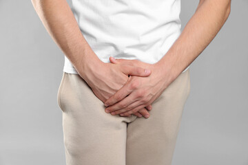 STD (sexually transmitted diseases). Man suffering from symptoms on grey background, closeup