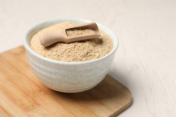 Oat bran in bowl and scoop on light table, closeup
