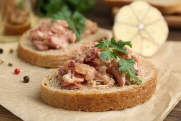 Sandwiches with canned meat, parsley, garlic and peppercorns on table, closeup