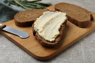 Fresh bread with butter and knife on grey table, closeup