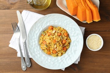Delicious pumpkin risotto served on wooden table, flat lay